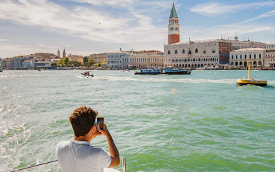 Visitor photographing St. Mark's Campanile from a Venice Panoramic Boat Tour.