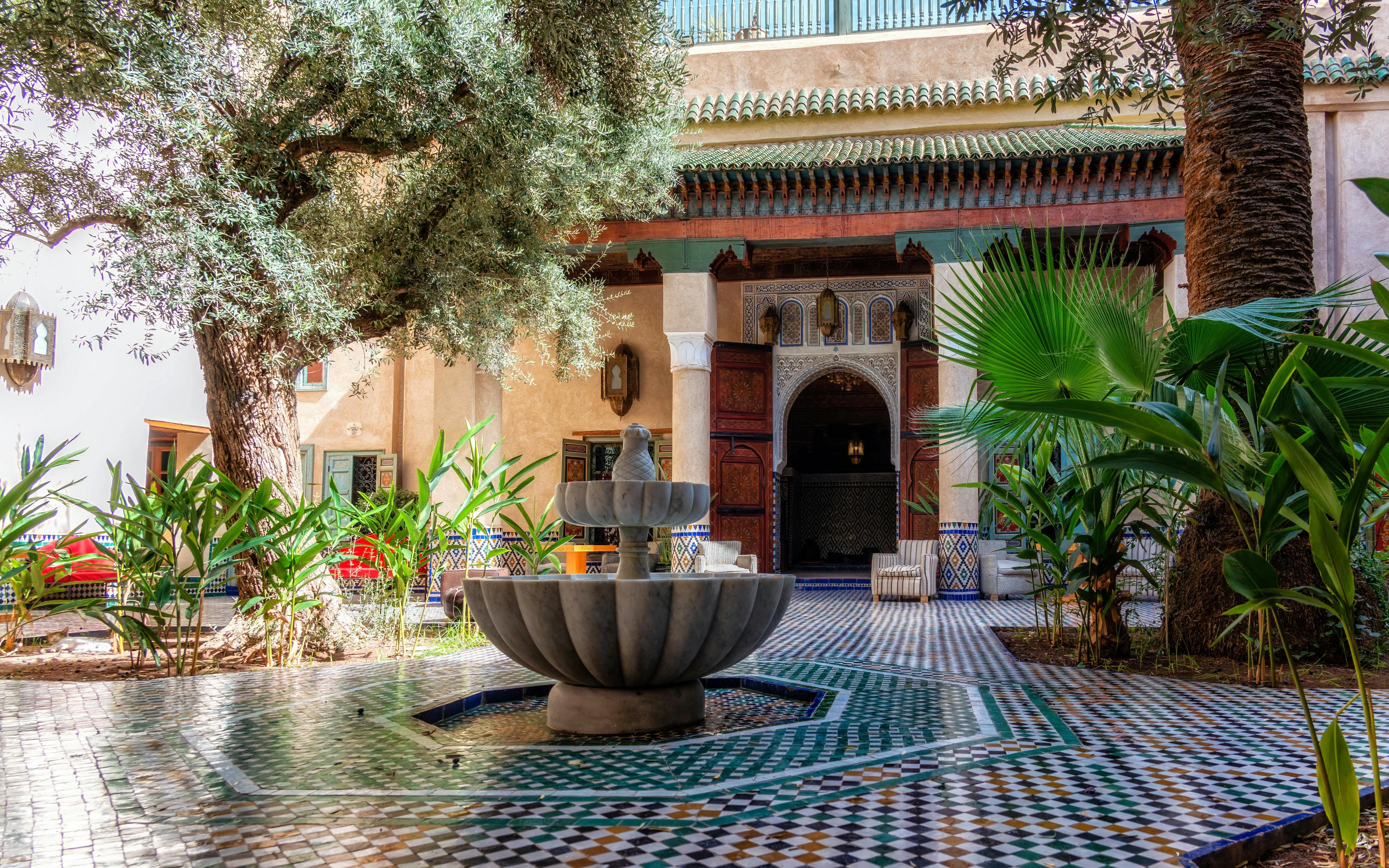 Courtyard with fountain at Moroccan Culinary Arts Museum, featuring traditional tilework and lush greenery.