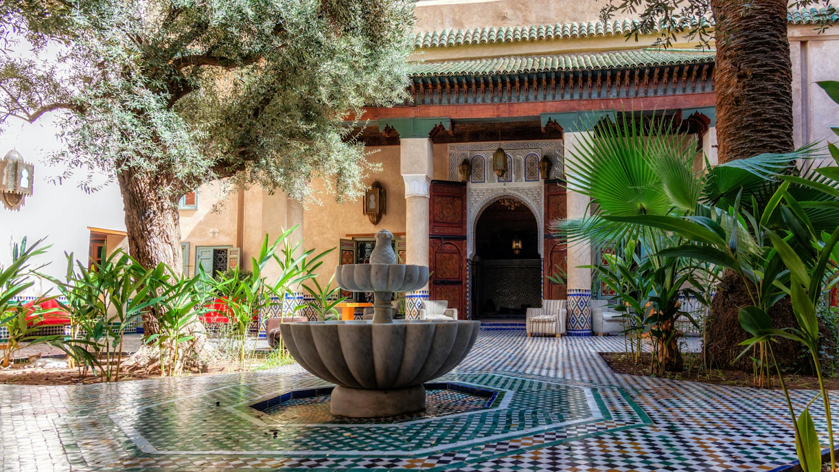 Courtyard with fountain at Moroccan Culinary Arts Museum, featuring traditional tilework and lush greenery.