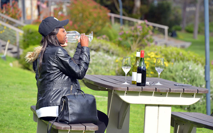 Tourist tasting wine at a picnic table in Constantia, South Africa.