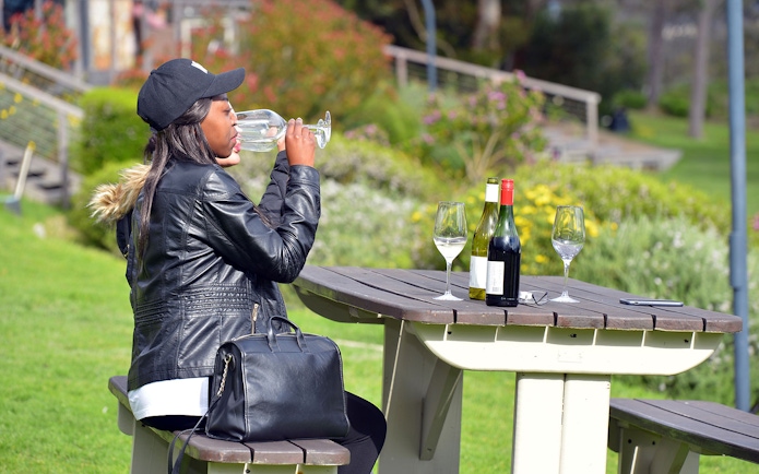 Tourist tasting wine at a picnic table in Constantia, South Africa.