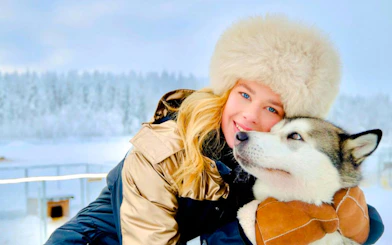 Guest embracing a Husky in a snowy landscape.