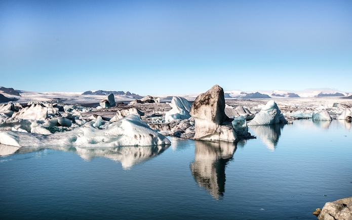 Icebergs floating in Jökulsárlón Glacier Lagoon, Iceland, with distant mountains.