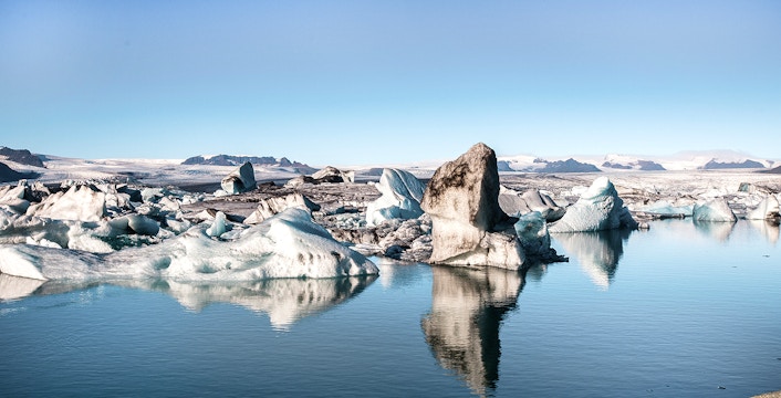 Icebergs floating in Jökulsárlón Glacier Lagoon, Iceland, with distant mountains.
