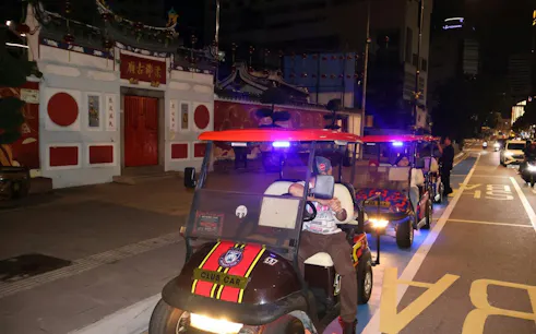 Buggy tour with foreign visitors driving past traditional building in Dubai at night.