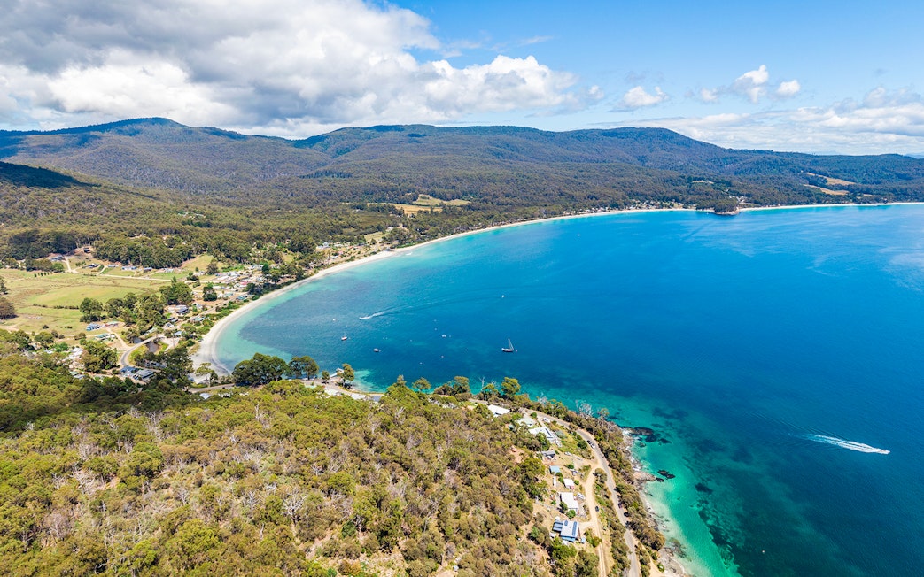 Aerial view of Bruny Island coastline with lush forests and clear blue waters, Tasmania.