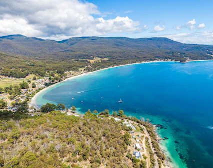 Aerial view of Bruny Island coastline with lush forests and clear blue waters, Tasmania.