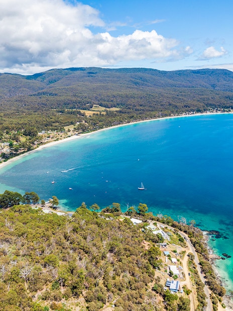 Aerial view of Bruny Island coastline with lush forests and clear blue waters, Tasmania.