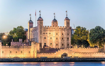 Tower of London illuminated at night, view from the Thames River.