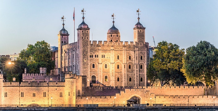 Tower of London illuminated at night, view from the Thames River.