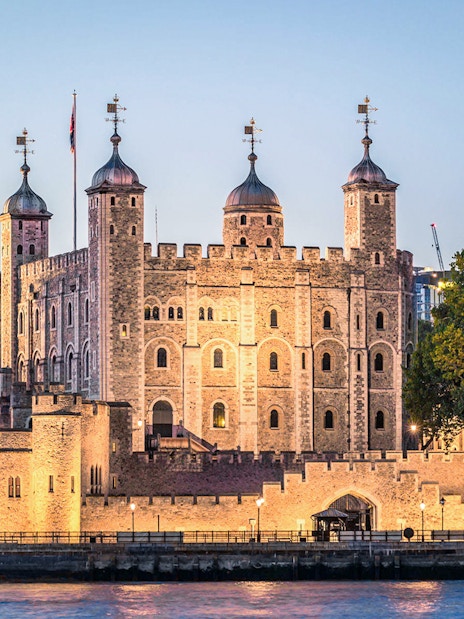 Tower of London illuminated at night, view from the Thames River.