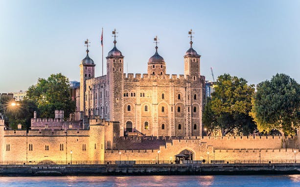 Tower of London illuminated at night, view from the Thames River.