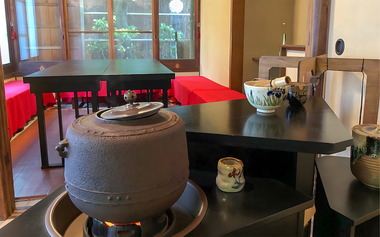 Traditional tea ceremony setup in a Kyoto machiya with tea utensils and a kettle.