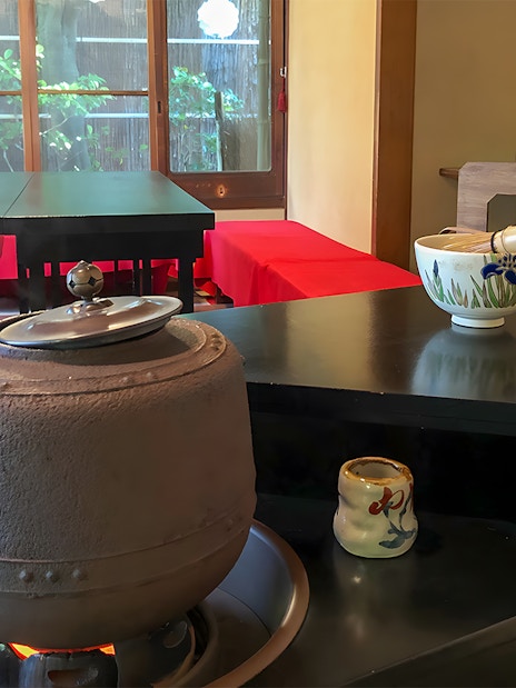 Traditional tea ceremony setup in a Kyoto machiya with tea utensils and a kettle.
