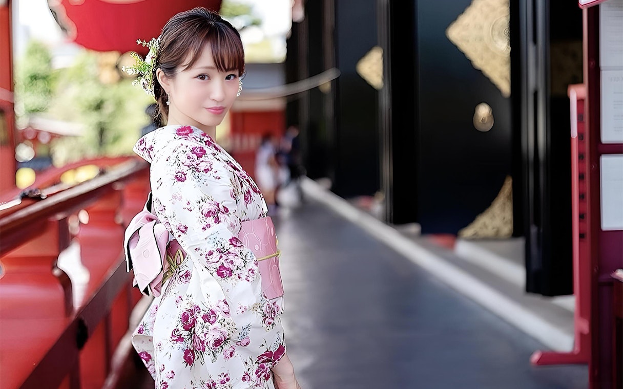Person in floral kimono at Asakusa, Tokyo, with traditional architecture in the background.