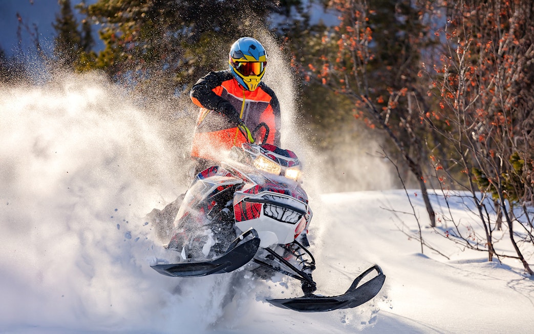 Snowmobile rider speeding through snowy forest near Zakopane.