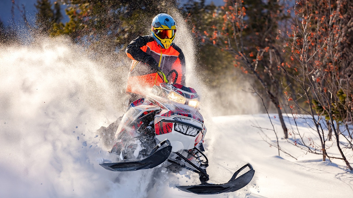 Snowmobile rider speeding through snowy forest near Zakopane.