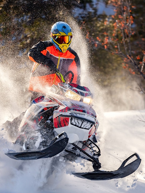 Snowmobile rider speeding through snowy forest near Zakopane.