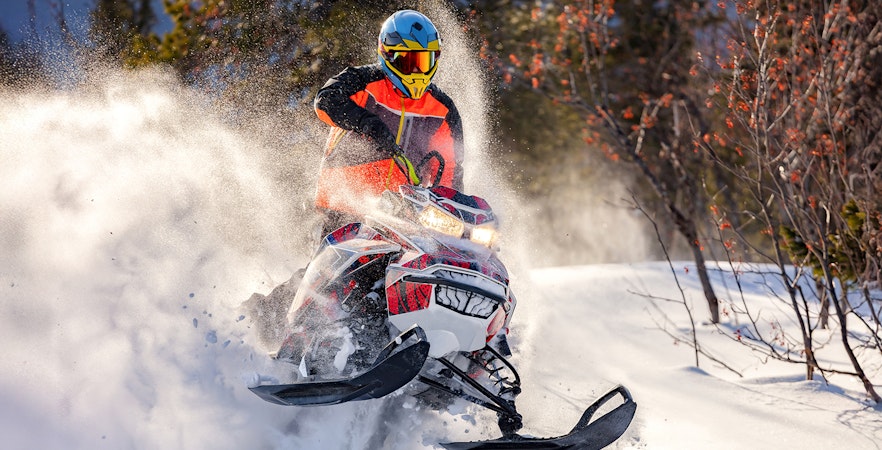 Snowmobile rider speeding through snowy forest near Zakopane.