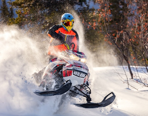 Snowmobile rider speeding through snowy forest near Zakopane.