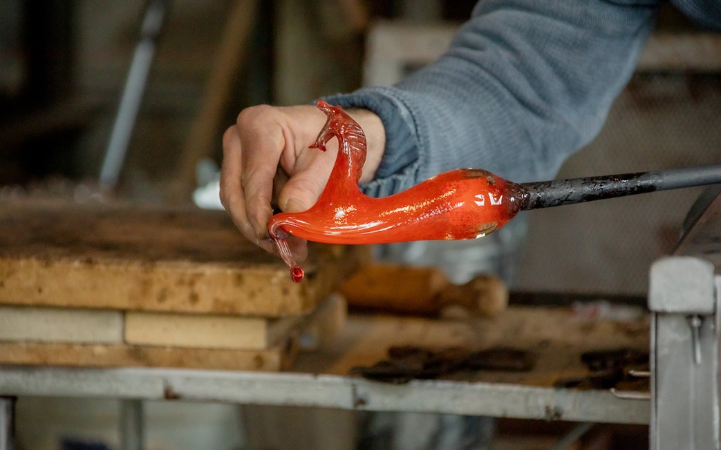 Glassblowing demonstration in Murano, Venice, with molten glass on a rod.