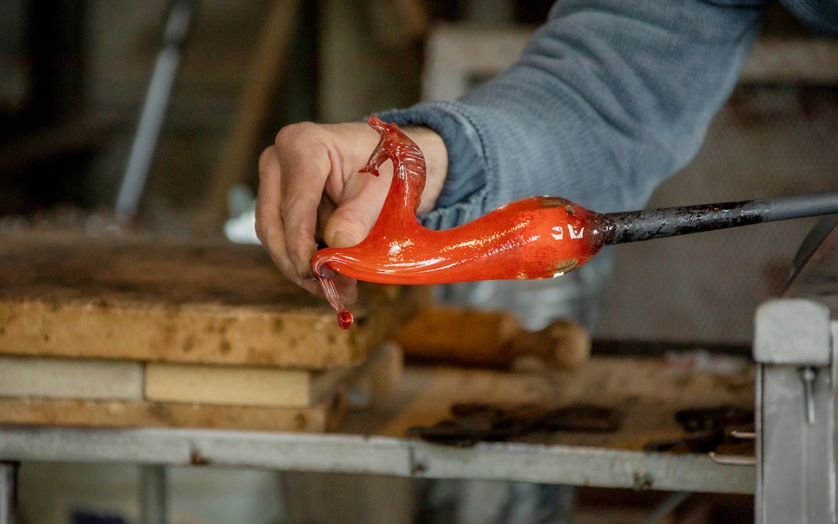 Glassblowing demonstration in Murano, Venice, with molten glass on a rod.