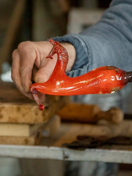 Glassblowing demonstration in Murano, Venice, with molten glass on a rod.