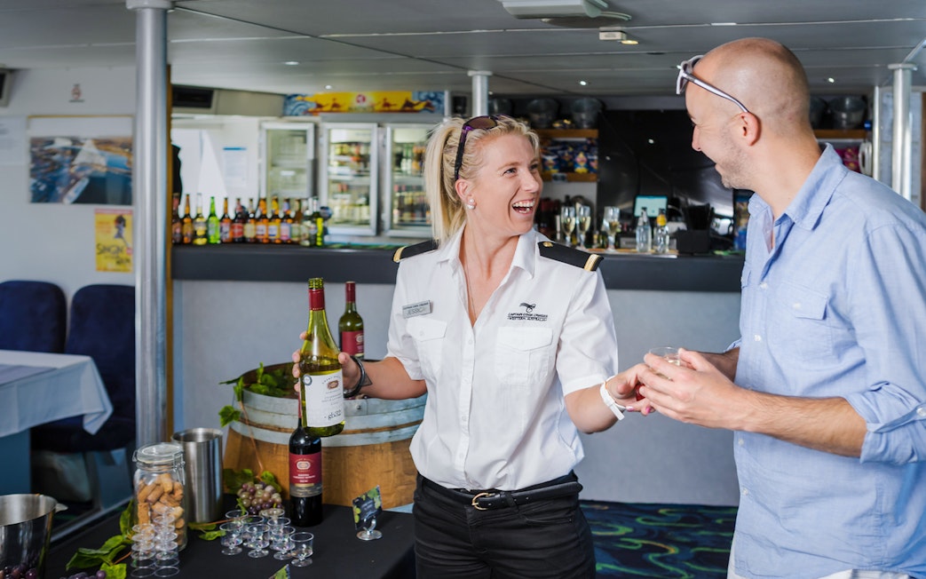 Server offering wine to a guest on a Swan River dining cruise.