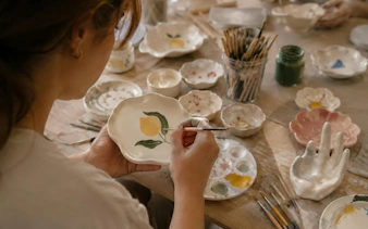 Sculpting and painting clay dish with lemon design at Krakow workshop.