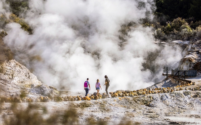 Tourists walking through steam at Hells Gate Geothermal Park.