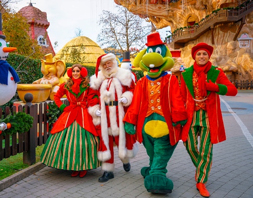 Santa Claus and friends walking at Gardaland Park with festive decorations.