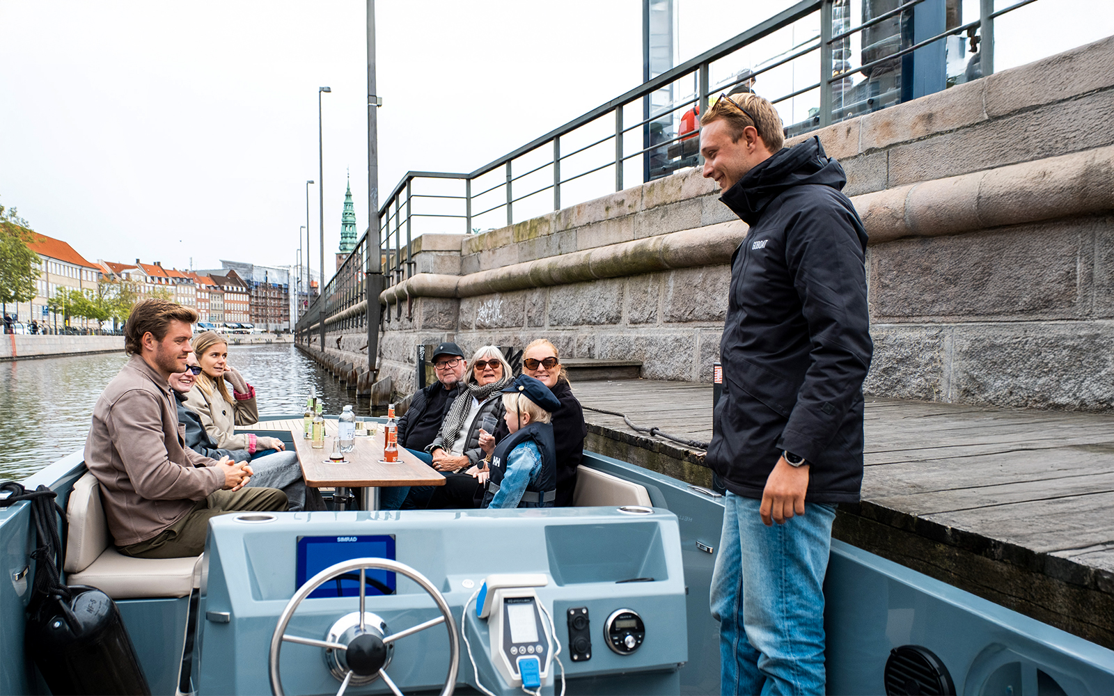 Guests on an electric boat tour in Copenhagen with captain pedaling along the canal.