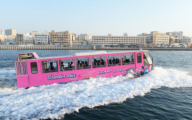 Dubai Wonder Bus cruising on water with cityscape in the background.