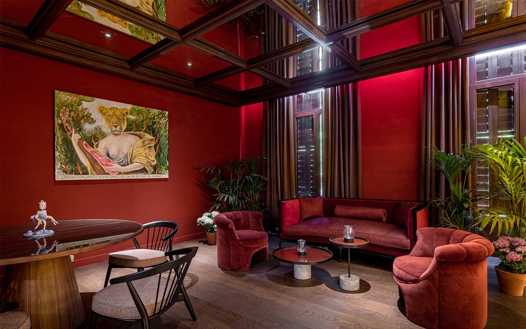 Elegant lounge with red decor and a painting of a lioness, setting for Flamenco De Leones Show.