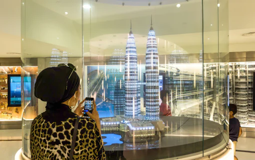 Visitor photographing Petronas Twin Towers model in Kuala Lumpur exhibit.
