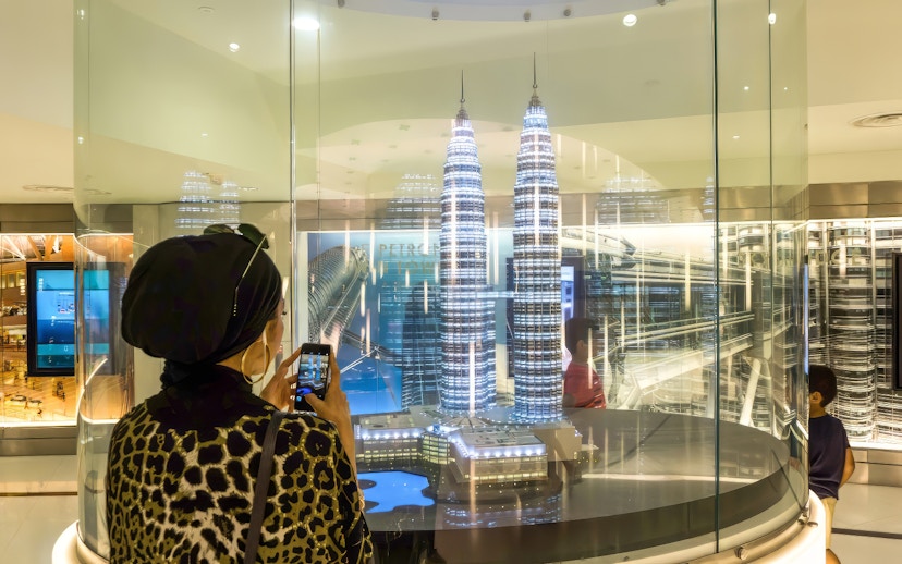 Visitor photographing Petronas Twin Towers model in Kuala Lumpur exhibit.