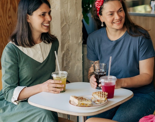 Women enjoying drinks and sandwiches at a café.