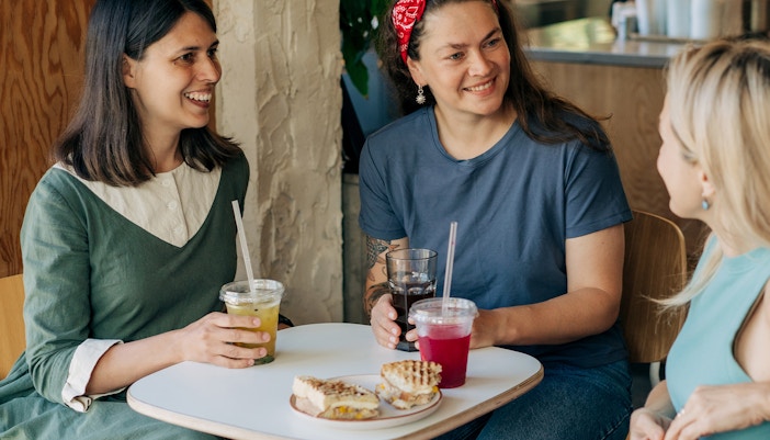 Women enjoying drinks and sandwiches at food market