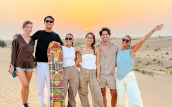 Group enjoying sunset during Evening Desert Safari Tour with sandboard, Abu Dhabi.