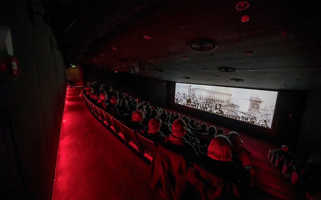 Visitors watching The Malta Experience audio-visual show in a dark theatre.