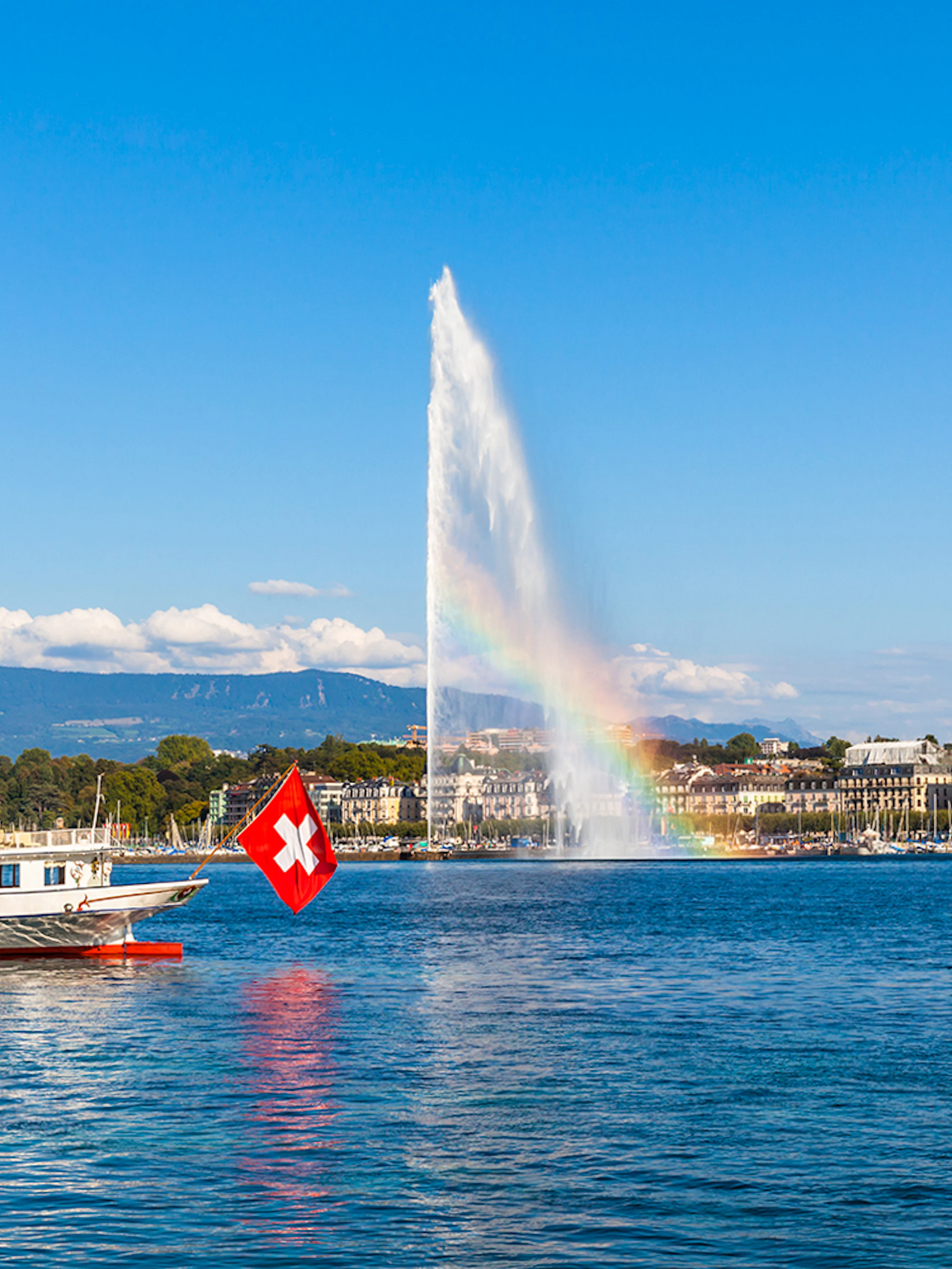 Lake Geneva with Jet d'Eau fountain and Swiss flag boat in the foreground.