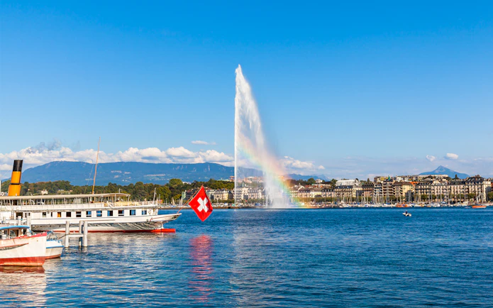 Lake Geneva with Jet d'Eau fountain and Swiss flag boat in the foreground.