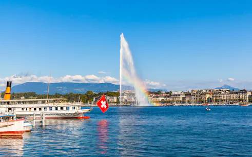 Lake Geneva with Jet d'Eau fountain and Swiss flag boat in the foreground.
