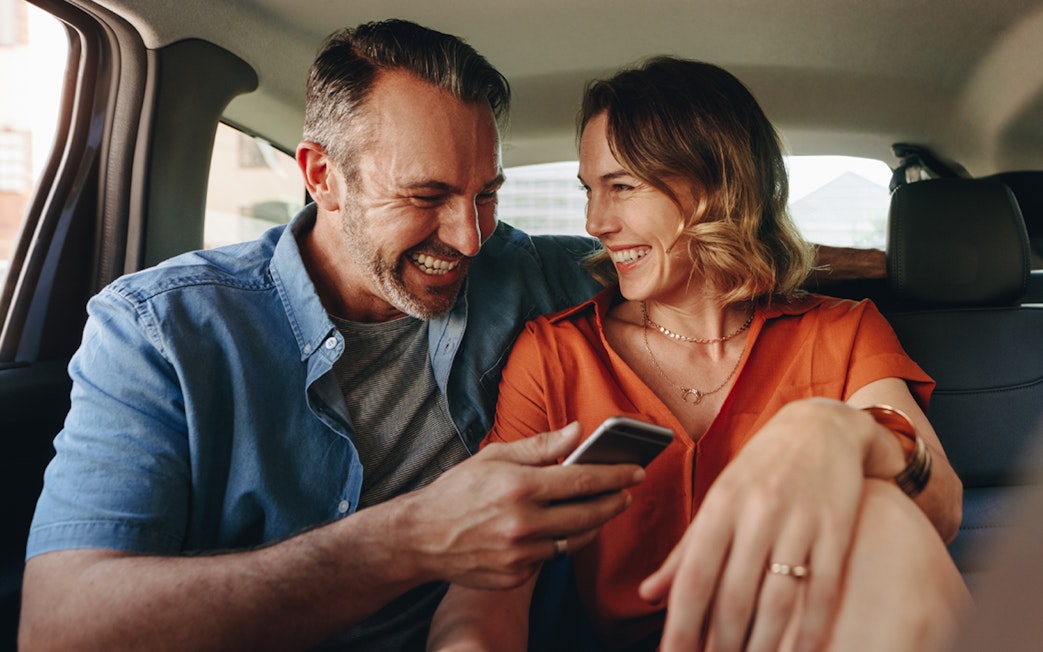Couple smiling in back seat during Zone 1 Half Day Transfers.