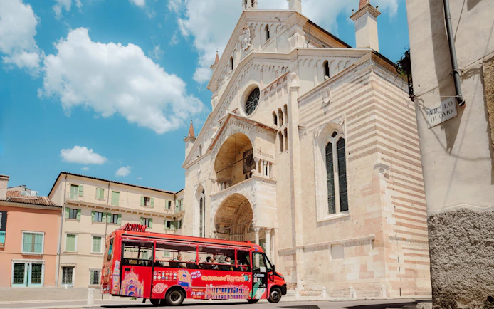 Red sightseeing bus in front of Verona Cathedral during City Sightseeing Verona Hop-on Hop-off Tour.