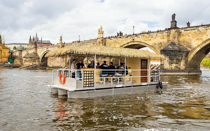 Tiki boat bar cruising near Charles Bridge in Prague.