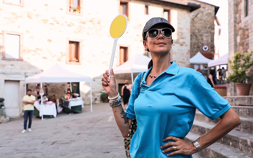 Tour guide holding a sign in a Chianti village during a wine tour from Florence.