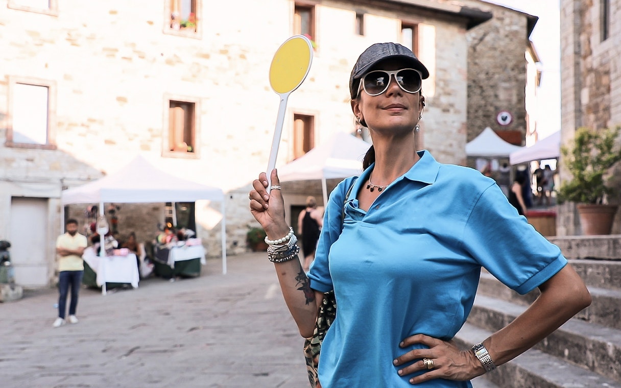 Tour guide holding a sign in a Chianti village during a wine tour from Florence.