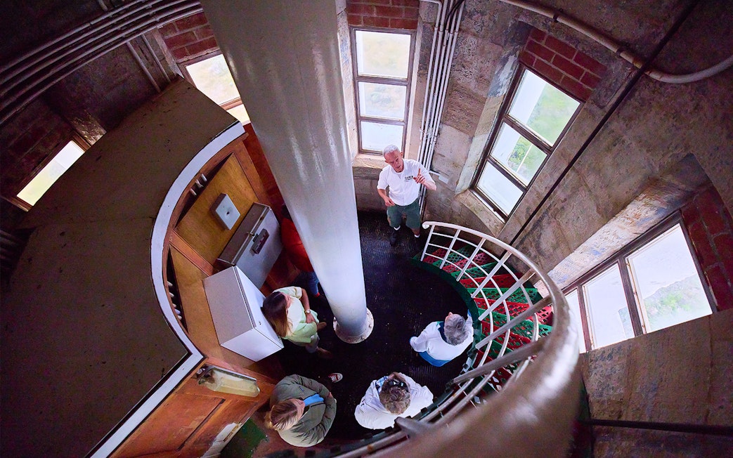 Tour group inside Cape Leeuwin Lighthouse, viewed from above on spiral stairs.
