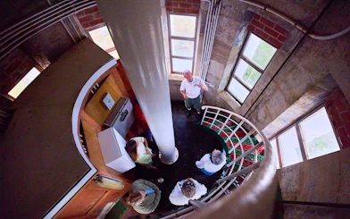 Tour group inside Cape Leeuwin Lighthouse, viewed from above on spiral stairs.
